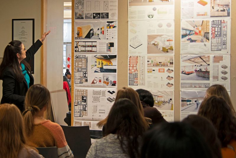 Student discusses drawing with faculty in Cowgill lobby.