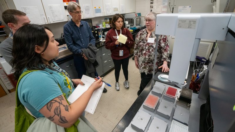 group of people looking at a lab machine 