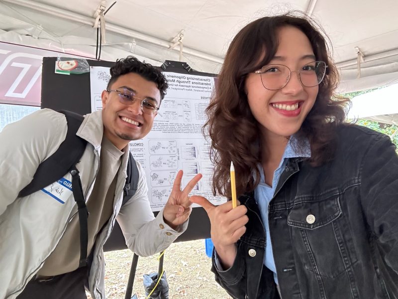 two people smiling in front of poster board