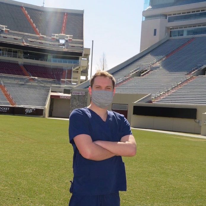 Preston Callaway with mask on standing in on the football field in Lane Stadium