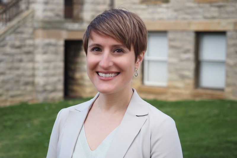 a woman stands smiling at the camera 