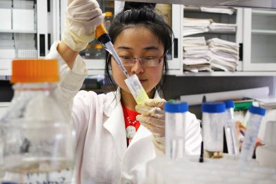 A faculty member looking inside a tube