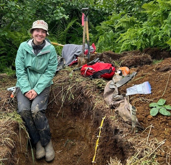 Elizabeth Eroshenko digging in a large hole in the soil