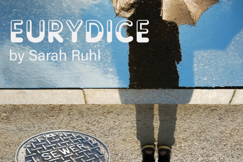 The shadow of a woman holding an umbrella, standing outside beside a sewer manhole colver.