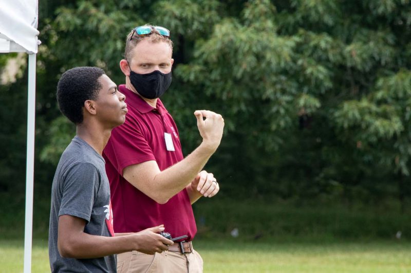 a drone pilot explains flight principles to a high school student 