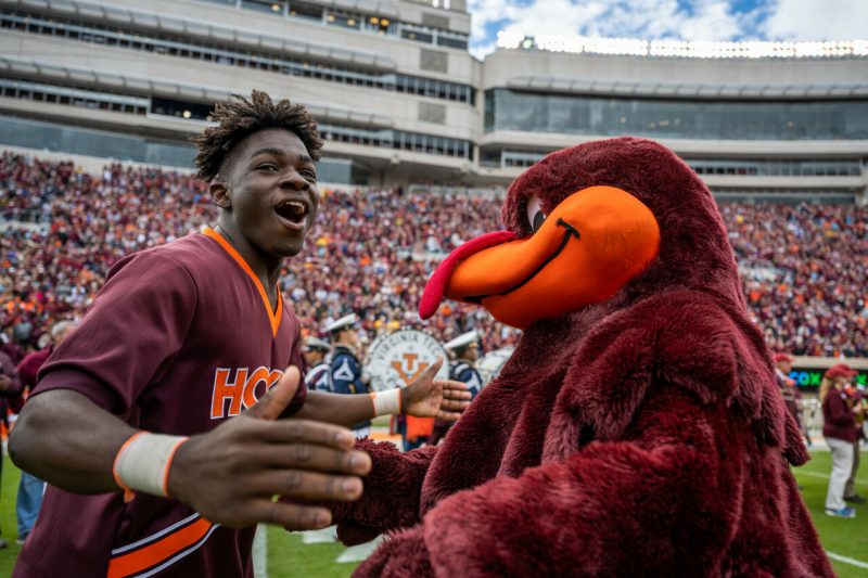 male cheerleader smiling with HokieBird