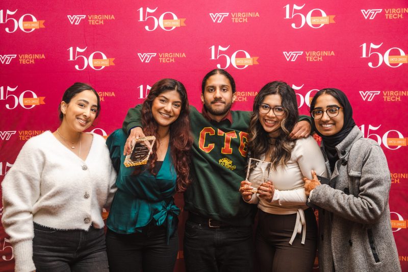 Student Organization Leadership Award winners holding awards, with arms linked, in front of a sesquicentennial banner.