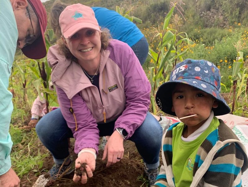 Amy Johnson, along with two other adults and a young boy in Peru, poses while digging for potatoes in a field.