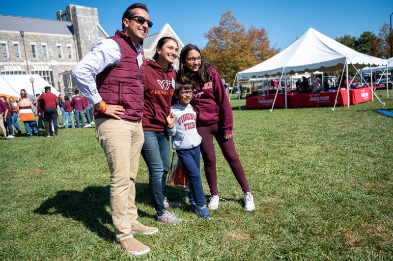 a family smiling posing outdoors on a lawn in front of a building