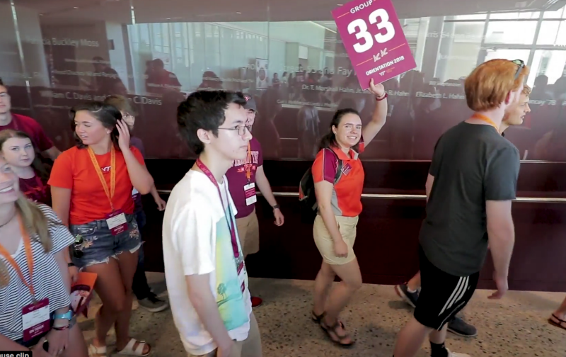 Students follow each other in a hall during orientation.
